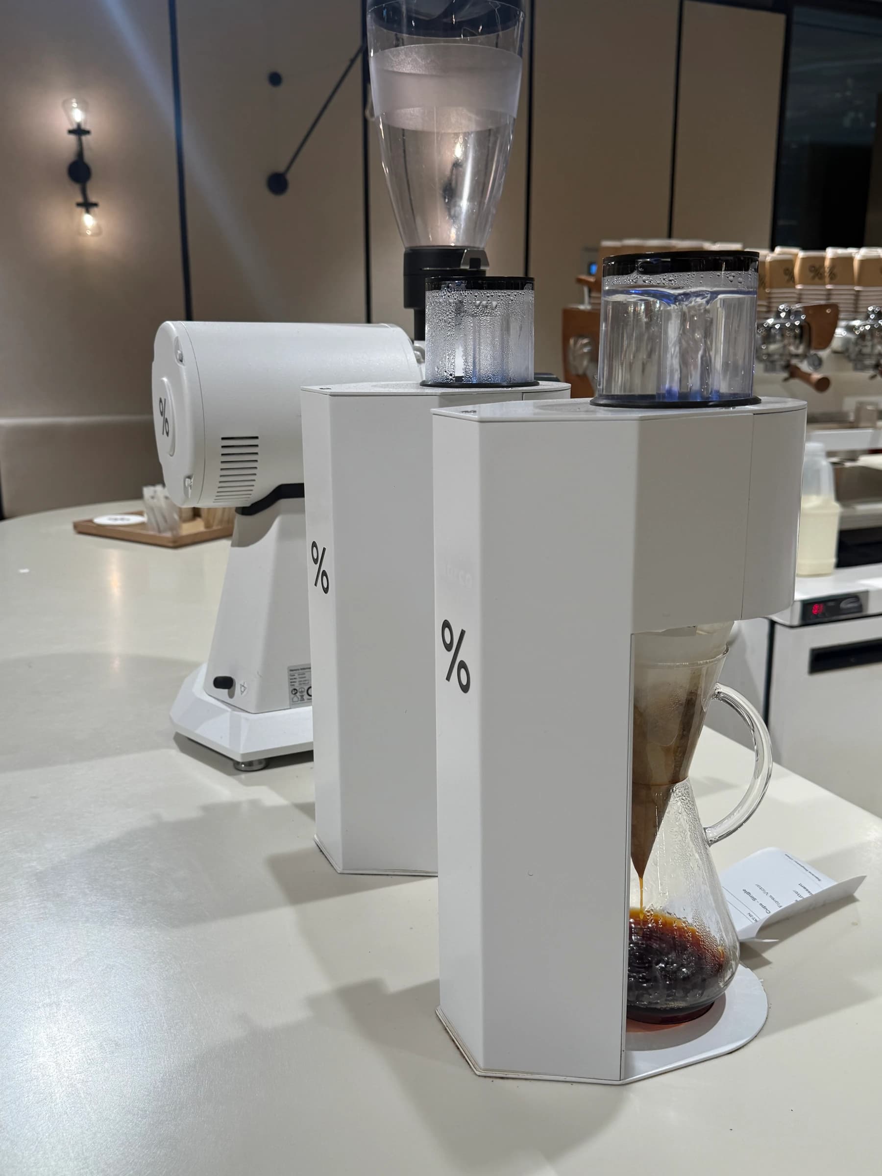 vertical postcard of %arabica battersea power station, the chemex pour-over bench in the apple-store-style room