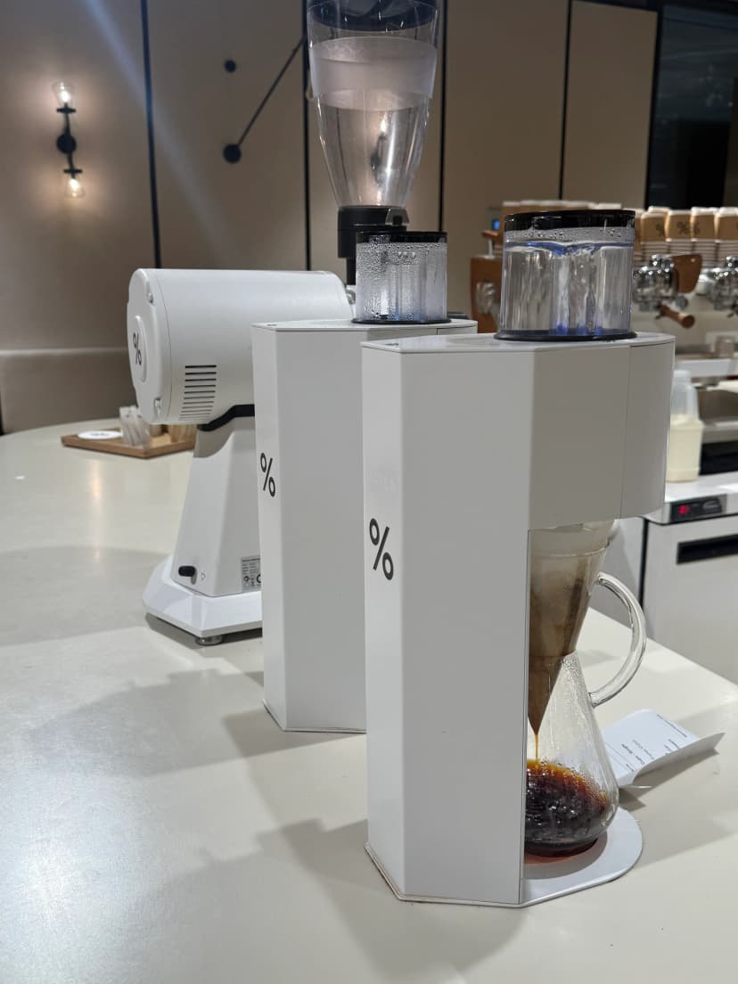 vertical postcard of %arabica battersea power station, the chemex pour-over bench in the apple-store-style room